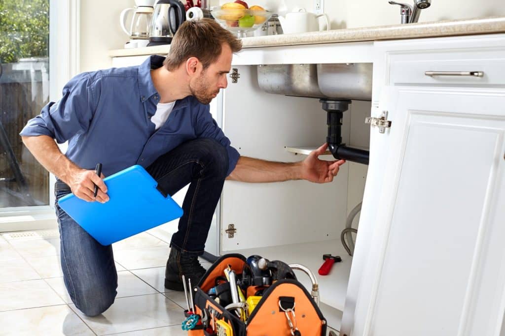 Plumbing inspection under a sink where pipe condensation may cause moisture damage