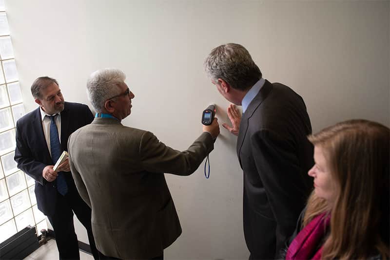 Certified lead inspector performing XRF lead paint testing on a painted interior wall